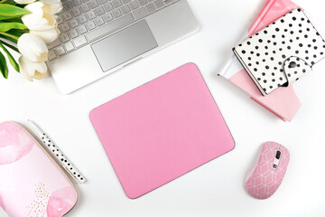 Pink mouse pad mockup. Styled with computer keyboard and modern desktop accessories. Negative copy space.