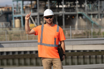 engineer man at construction site with raised finger wearing hardhat. engineer man at construction...