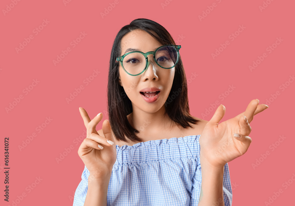 Wall mural beautiful asian woman in stylish eyeglasses on pink background