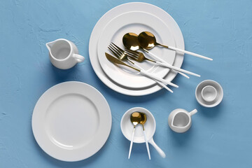 Clean plates with set of golden cutlery on blue grunge table