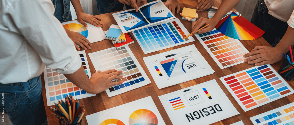Poster Graphic designer brainstorm logo and graphic art at busy creative studio workshop. Experiment and brainstorm color palette and pattern at workspace table for creative design. Panorama shot. Scrutinize