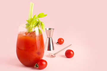 Glass of bloody mary with celery and tomatoes on pink background