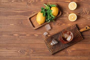 Boards with glass of ice tea and lemon on wooden background