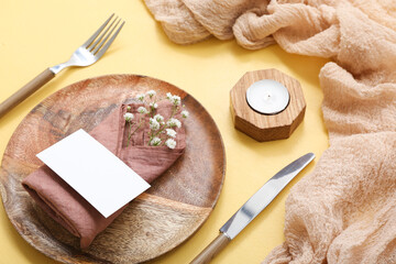 Beautiful table setting with gypsophila flowers, blank invitation card and candle on yellow table