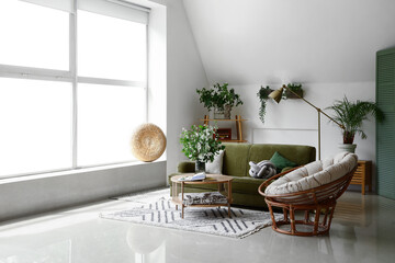 Interior of light living room with green sofa and blooming jasmine flowers on coffee table