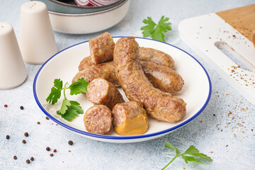 Plate of tasty homemade sausages on light background