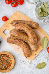 Wooden board of tasty homemade sausages on light background