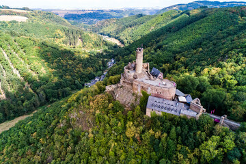 aerial view rock with medieval castle Ehrenburg on it near moselle river in Brodenbach with forest hills - 616349048