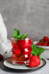 Glass of infused water with strawberry and mint on grey background