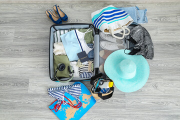 Suitcase with clothes, beach accessories, passport and tickets on floor. Travel concept