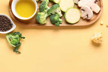 Fototapeta na wymiar Wooden board with fresh vegetables on yellow background
