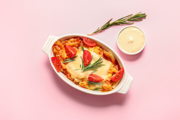 Baking dish of pasta with tomato sauce and cheese on pink background