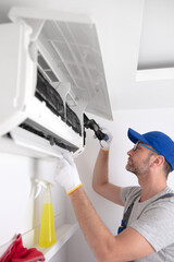 Service guy cleaning and maintaining air condition unit.