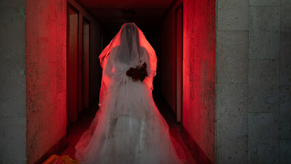 Ghostly figure of woman in wedding dress walking along a creepy hotel in red light.