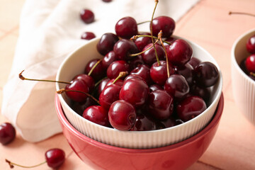 Bowl with sweet cherries on pink tile table