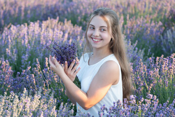 Beautiful girl smile in lavender flowers field. teen girl holding a lavender bouquet of flowers. Portrait of a beautiful young girl in a lavender field. Girl enjoying blooming lavender field
