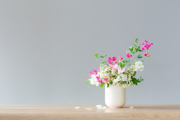 summer flowers in ceramic cup on light background