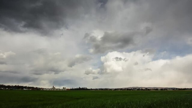 timelapse with a church in a valley and green field with dense storm and rain