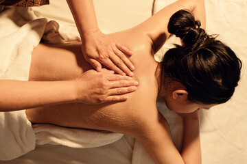 Top view, Masseuse hand applying salt scrub on back female customer at cosmetology spa centre....