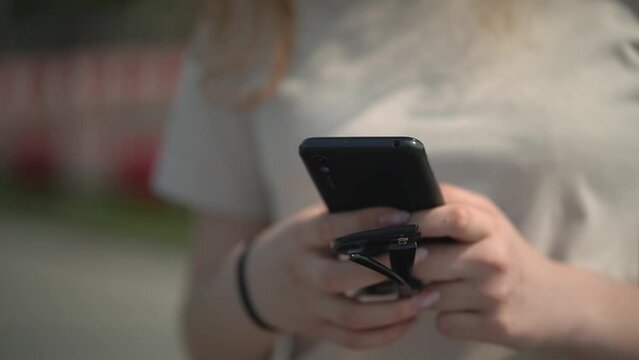 teenage girl is typing a text message on a smartphone. teenage girl is waiting for someone. teen date. close-up. High-quality Full HD video recording 