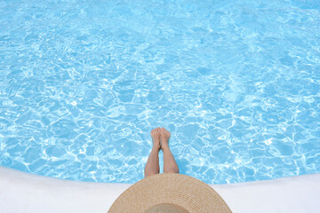 Woman in a hat sitting on the edge of the pool