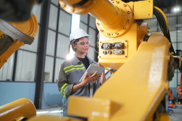 Fototapeta premium Robotic Arm engineer check on equipment in its with software of an Artificial Intelligence, Programming development technology work. Female industrial engineer working at automated robotic factory..