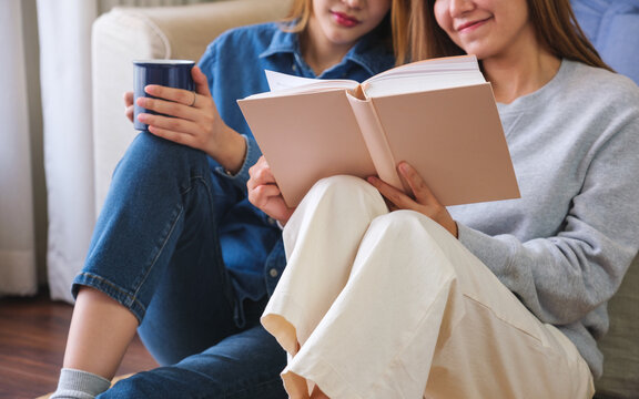 Closeup image of a young couple women enjoyed drinking coffee and reading books together at home