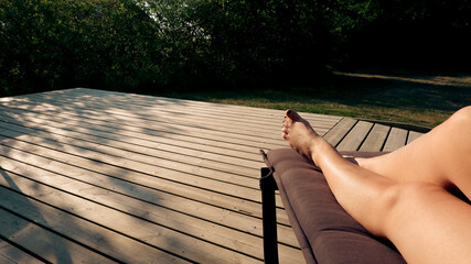 Beautiful woman legs sunbathing on lounger at the terrace. - Powered by Adobe