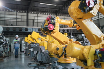 Woman working intently on a complicated industry 4.0 robot plant in technology factory.