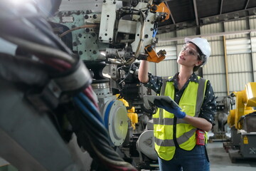 Woman working intently on a complicated industry 4.0 robot plant in technology factory.