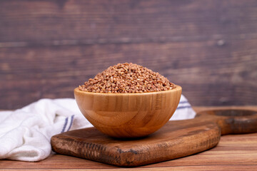 Buckwheat on wood background. Buckwheat grains in wooden bowl