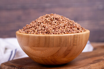 Buckwheat on wood background. Buckwheat grains in wooden bowl