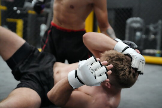 MMA Fight Takedown: Two mixed martial arts fighters locked in a ground struggle, one attempting a takedown while the other defends, showcasing the intensity and physicality of the sport.