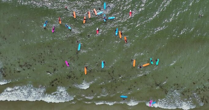 Surfers ride the waves on a beach with clear water