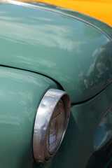 Headlight on pastel green retro car. Closeup.