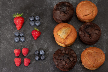 Homemade chocolate and vanilla muffins with fruit on a dark background. Sill life food photography.