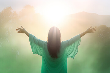 Happy young woman standing in a natural sunrise with raising arms