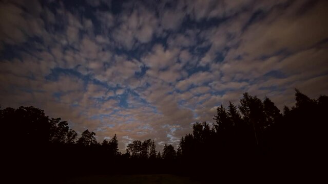 Astro time lapse with sunrise over forest. Cloudy sky time lapse.