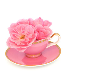 Fototapeta na wymiar Pink rose flower arrangement in tea cup on white. Surreal fun food composition. Flowers have calming, sedative and anti anxiety health benefits and can reduce risk of heart disease.