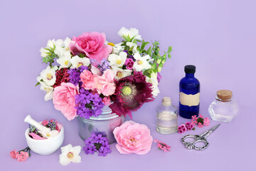 Medicinal flowers and herbs for naturopathic herbal medicine. Flower essences for natural remedies on lilac background with essential oil bottles.