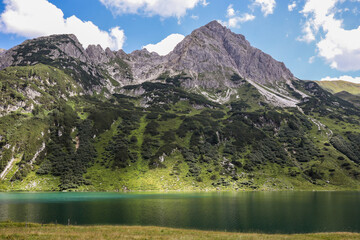 Fototapeta na wymiar Green Landscape of Rocky Mountain Peak and Alpine Lake in Austria. Tappenkarsee Tranquil Scene during Summer Day.