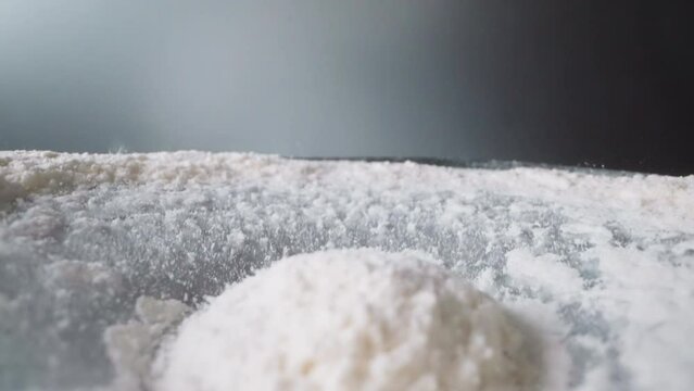 Pile of white starch bounces and spills into shaken vessel. Finely ground foodstuff moves up and down. Movement of powdered ingredient for cooking macro