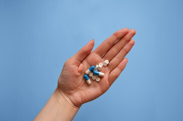 tablets and capsules on the palm of your hand on a blue background, photo for a medical clinic, banner for a medical website, day of a medical worker