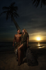 Portrait of couple tribal costume next to palm against sunset