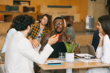 Handsome black male person listening to his Caucasian male business person explaining new advertising strategy