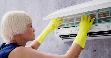 Young Woman Cleaning Air Conditioning System