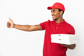African American pizza delivery man picking up pizza boxes over isolated white wall giving a thumbs...