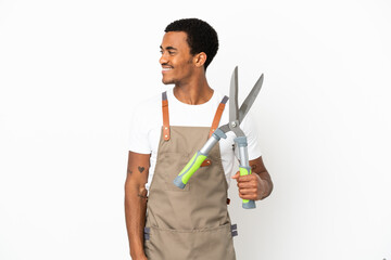 African American gardener man holding pruning shears over isolated white background looking to the...