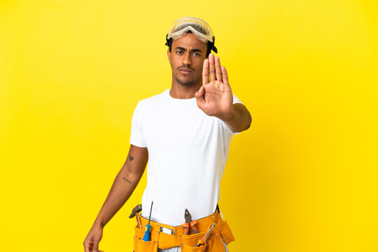 African American electrician man over isolated yellow wall making stop gesture