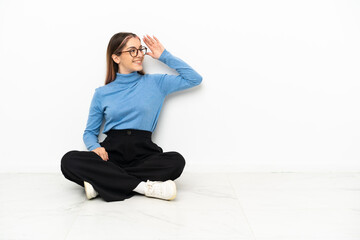 Young Caucasian woman sitting on the floor has realized something and intending the solution